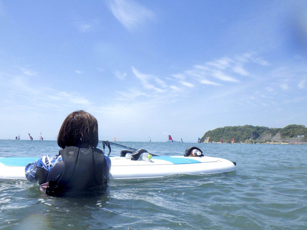 逗子海岸でウインドサーフィンを楽しみながら水に浸かって休憩